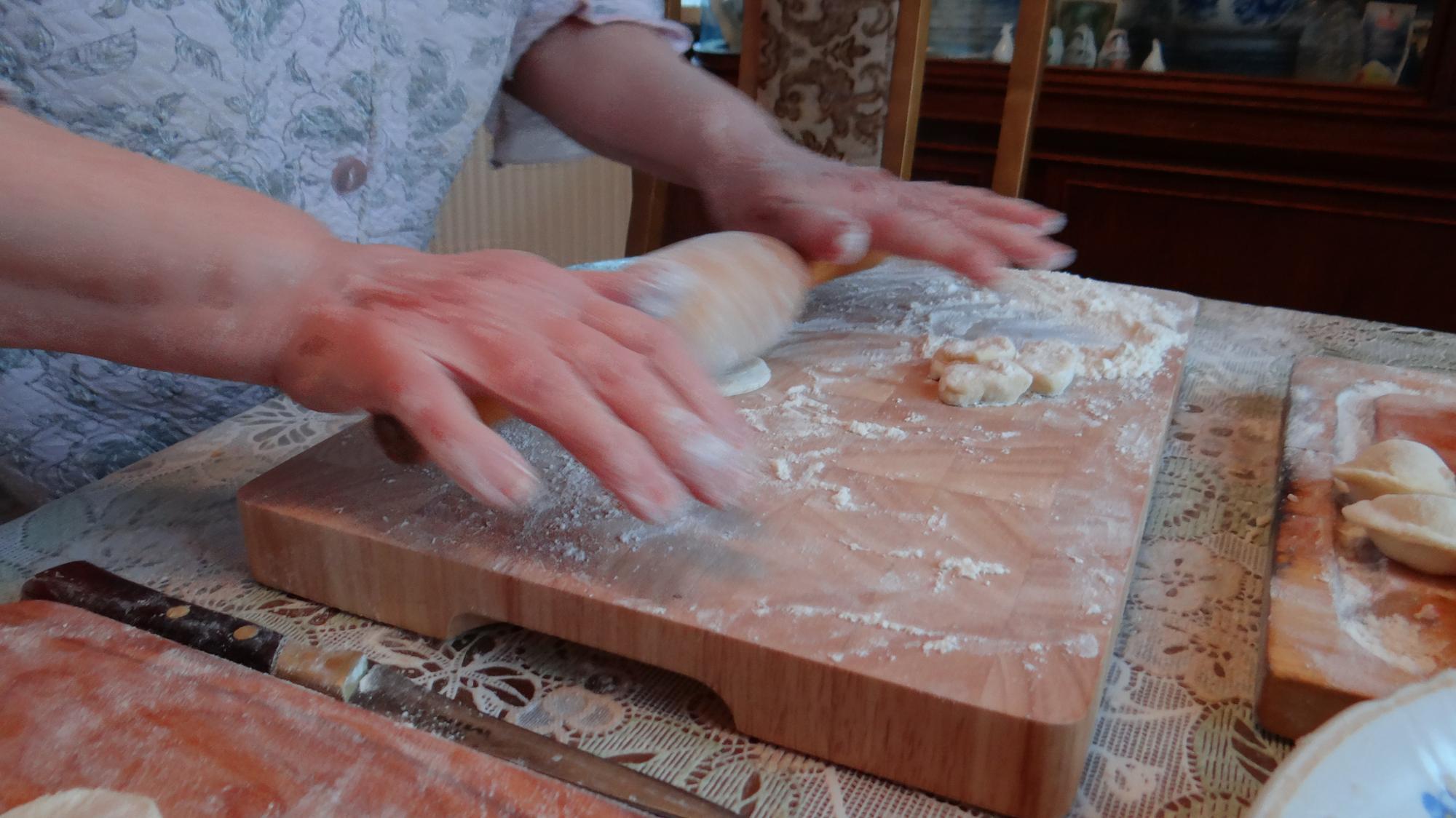 Hands shaping dough on wooden board