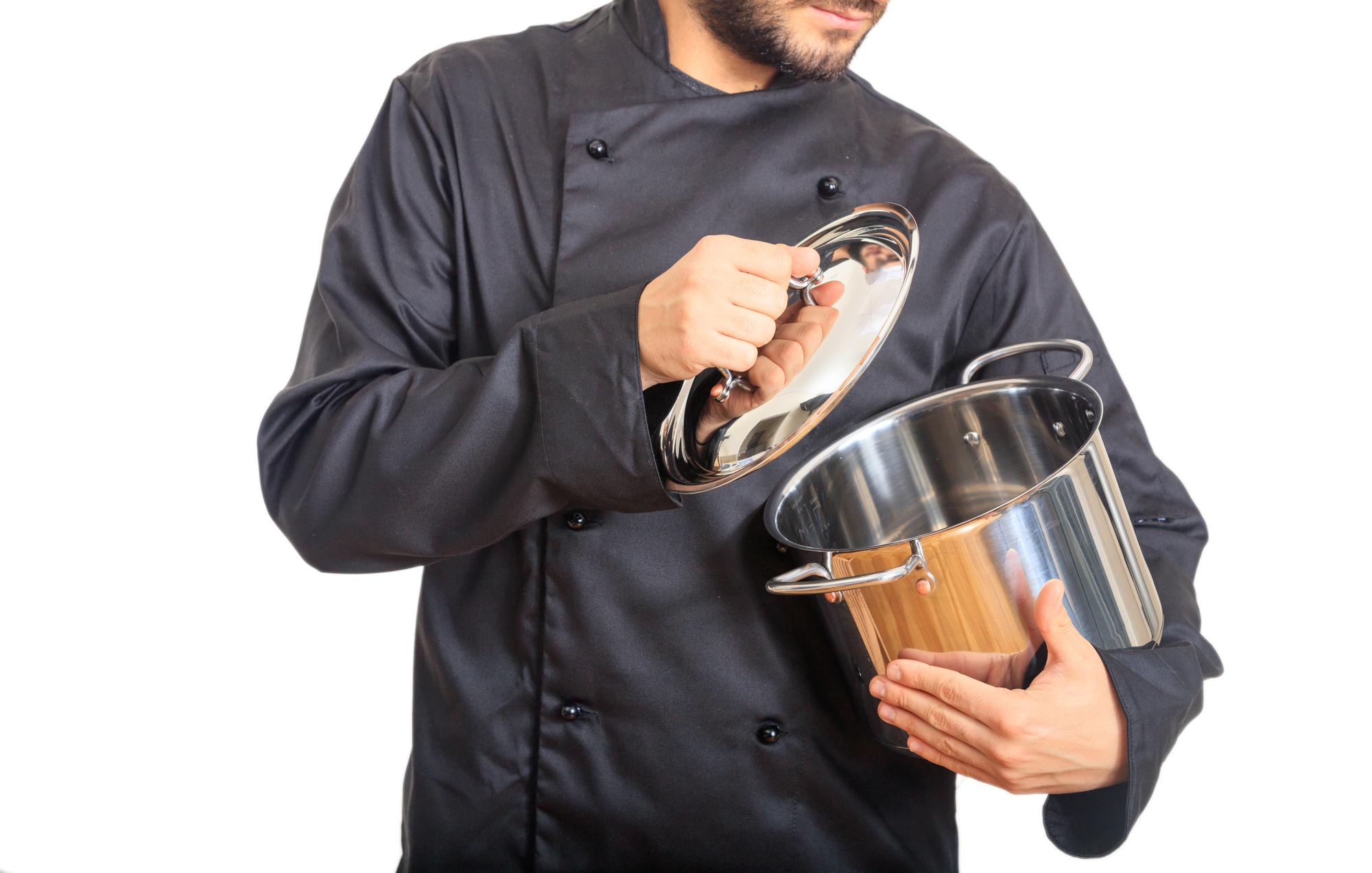 Chef seasoning a pan in warm light